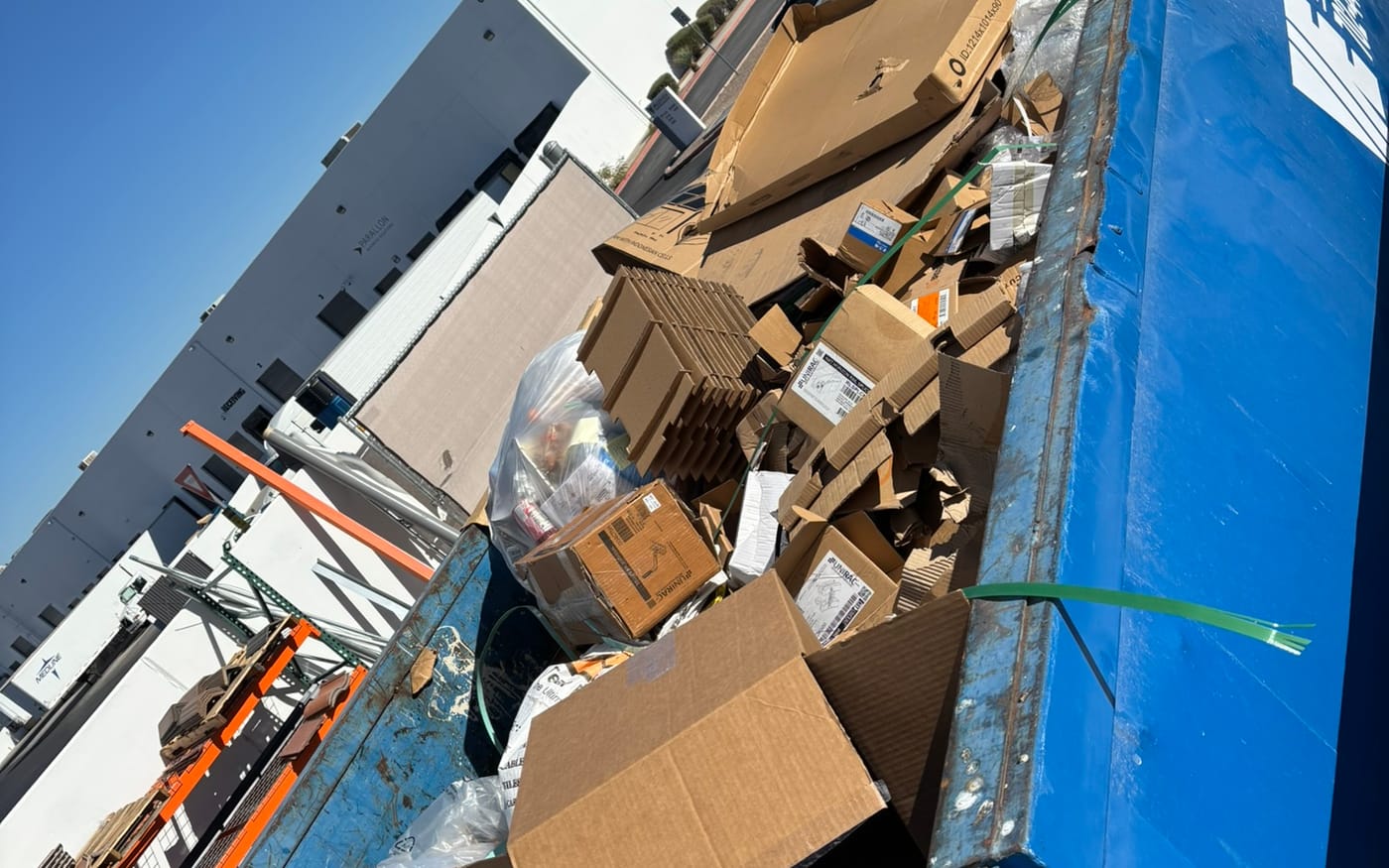 A roll-off container overfilled with cardboard and packaging before compaction.
