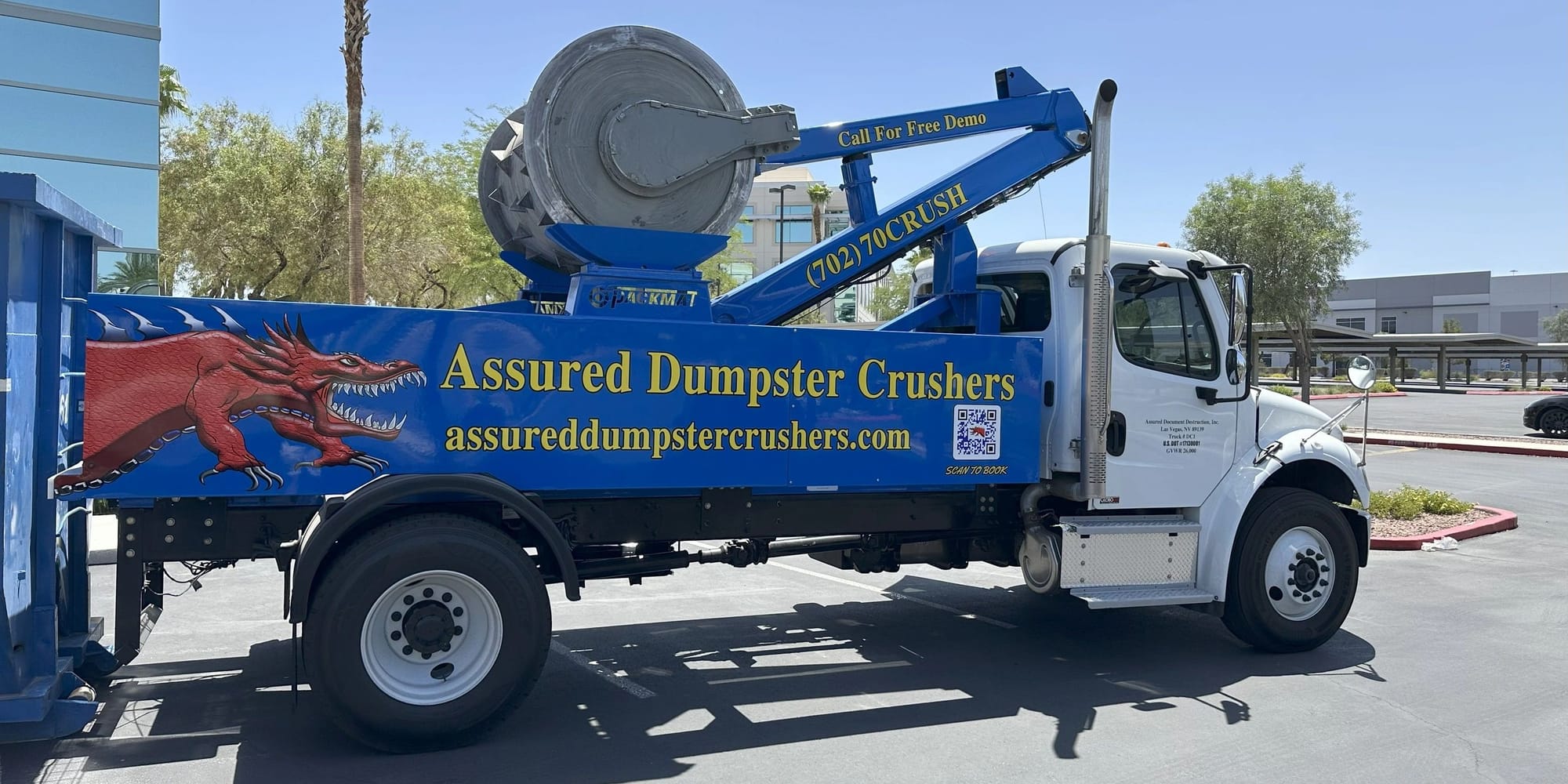 The Assured Dumpster Crushers truck with its 3-ton hydraulic drum, backed up to a roll-off container in Las Vegas.